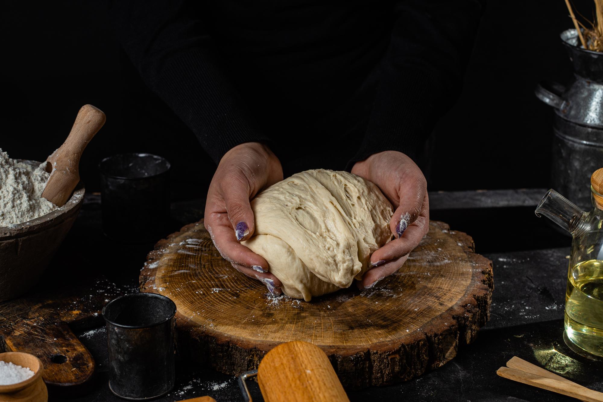 chef shaping rustic sourdough loaf in warm kitchen